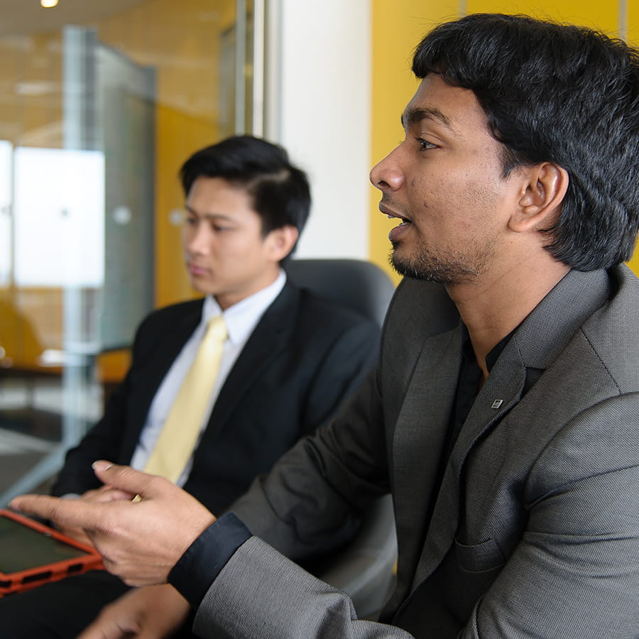 students in business attire in the, one student gestures left while one in background looks on