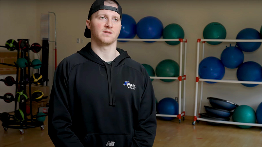 An Exercise & Health Sciences Student stands in front of exercise equipment