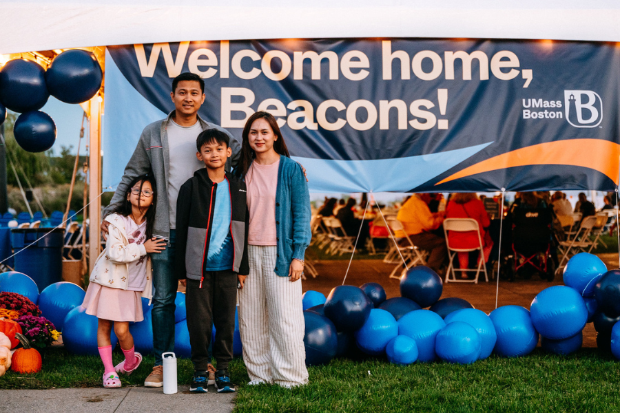 A family standing in front of a banner that says 