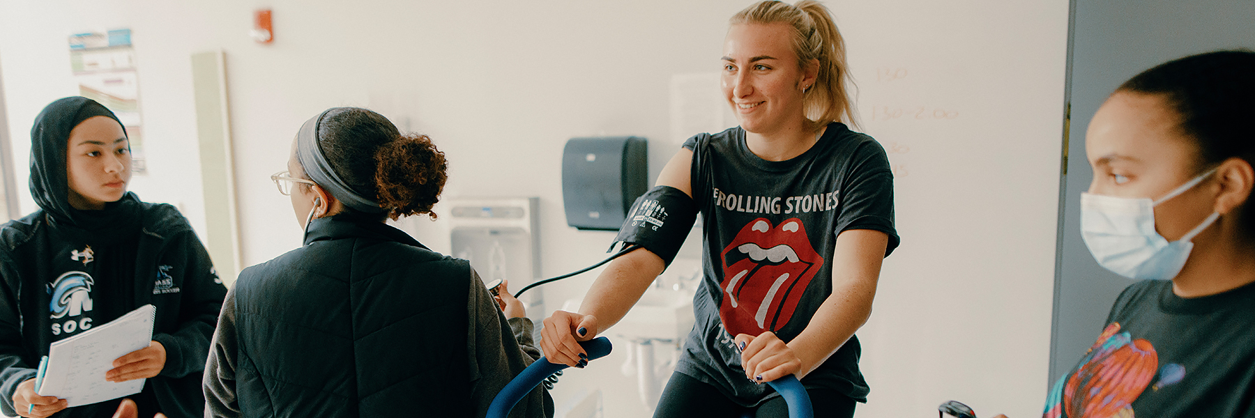 Students monitor classmate on an exercise bike lab.